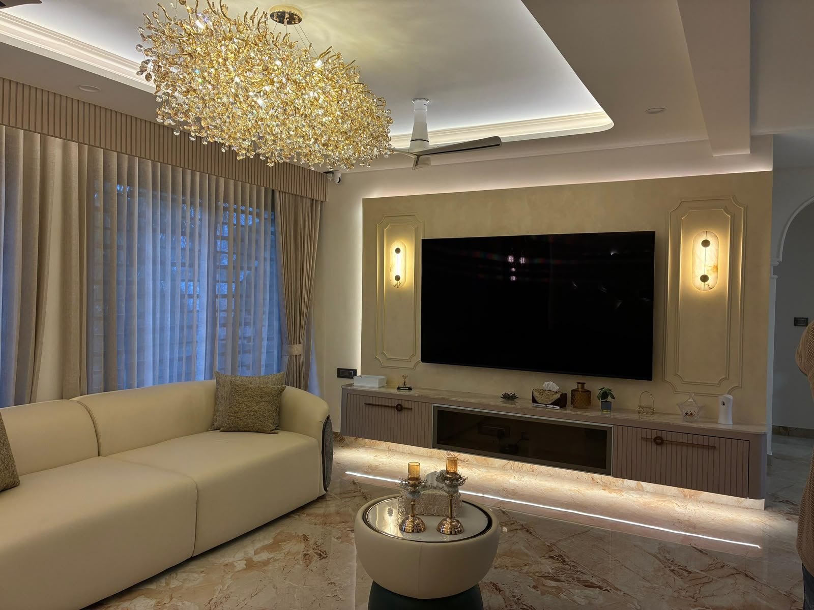 Living room with a warm lit TV wall and cream sofas
