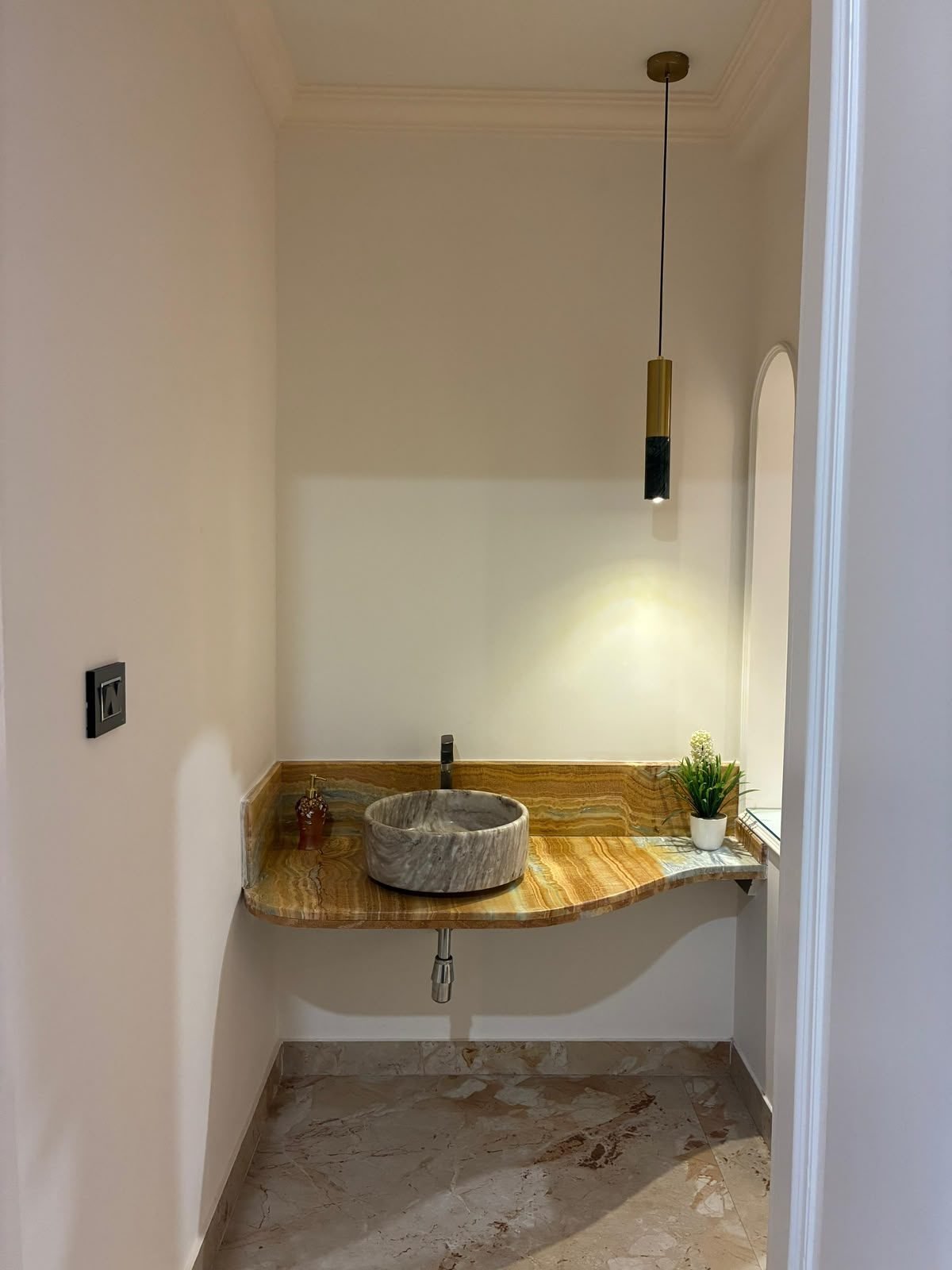 Powder room basin on a stone counter with a pendant light
